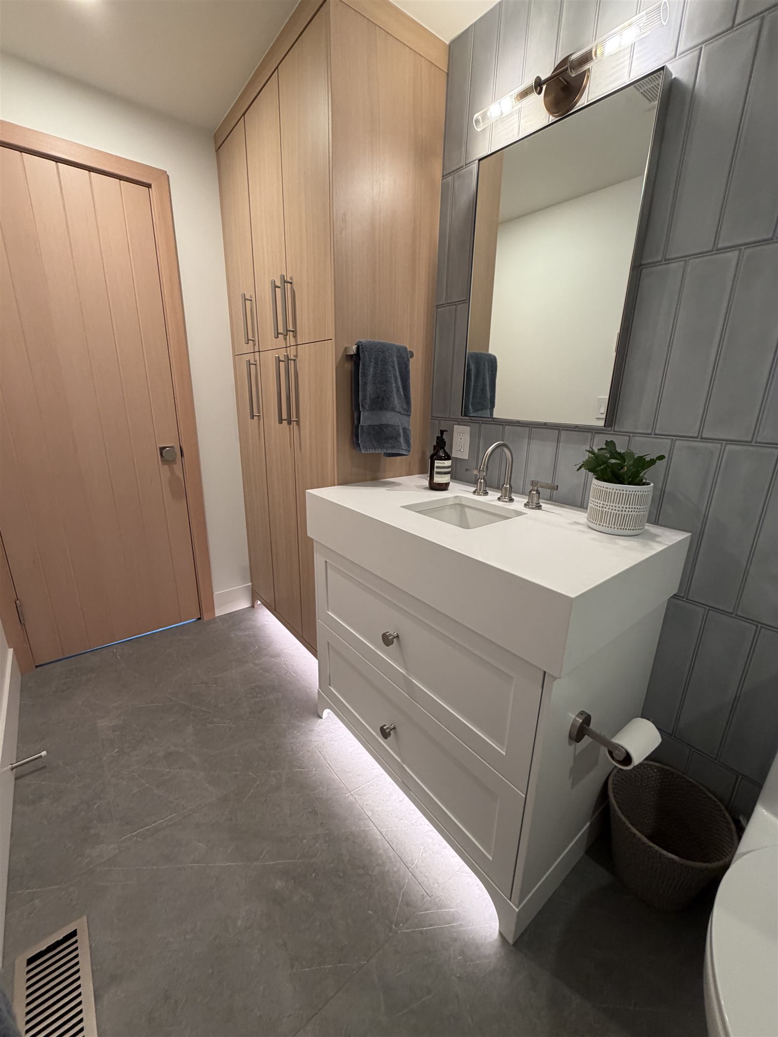 Spa-style bathroom with a floating white vanity, oak tall cabinetry, and gray tile