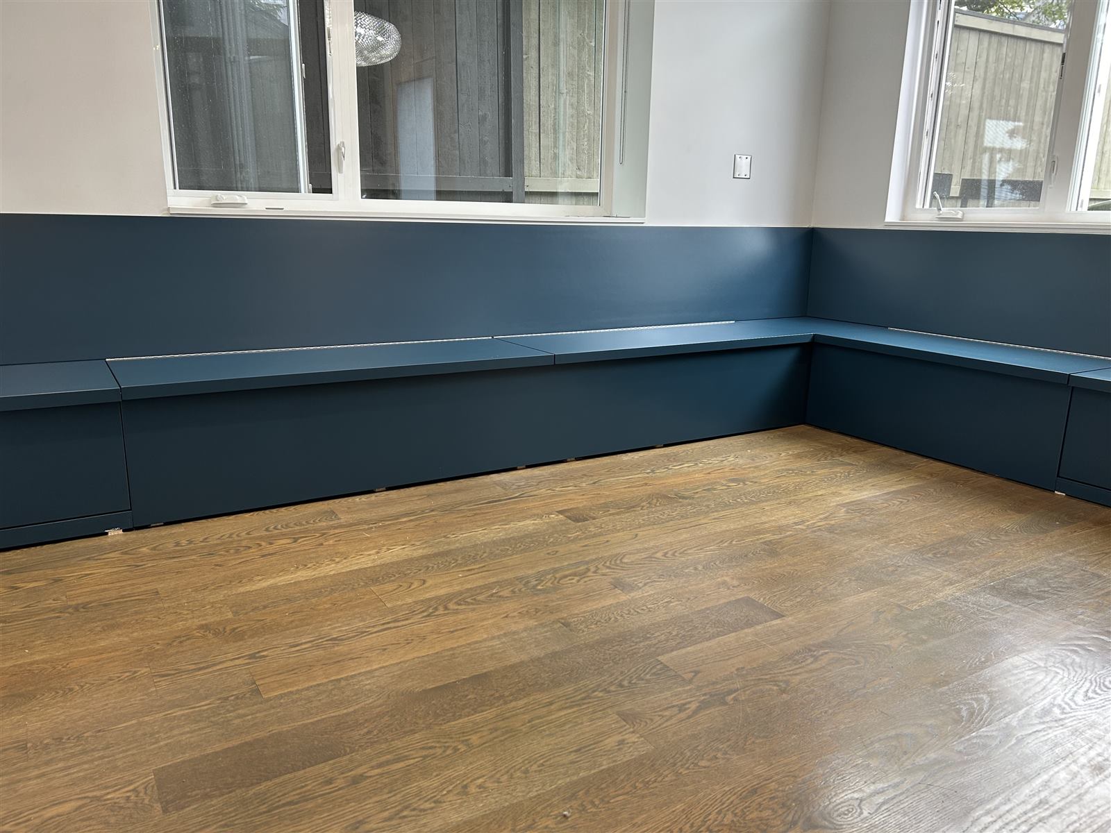 Built-in navy blue L-shaped bench seating along two walls with a window above