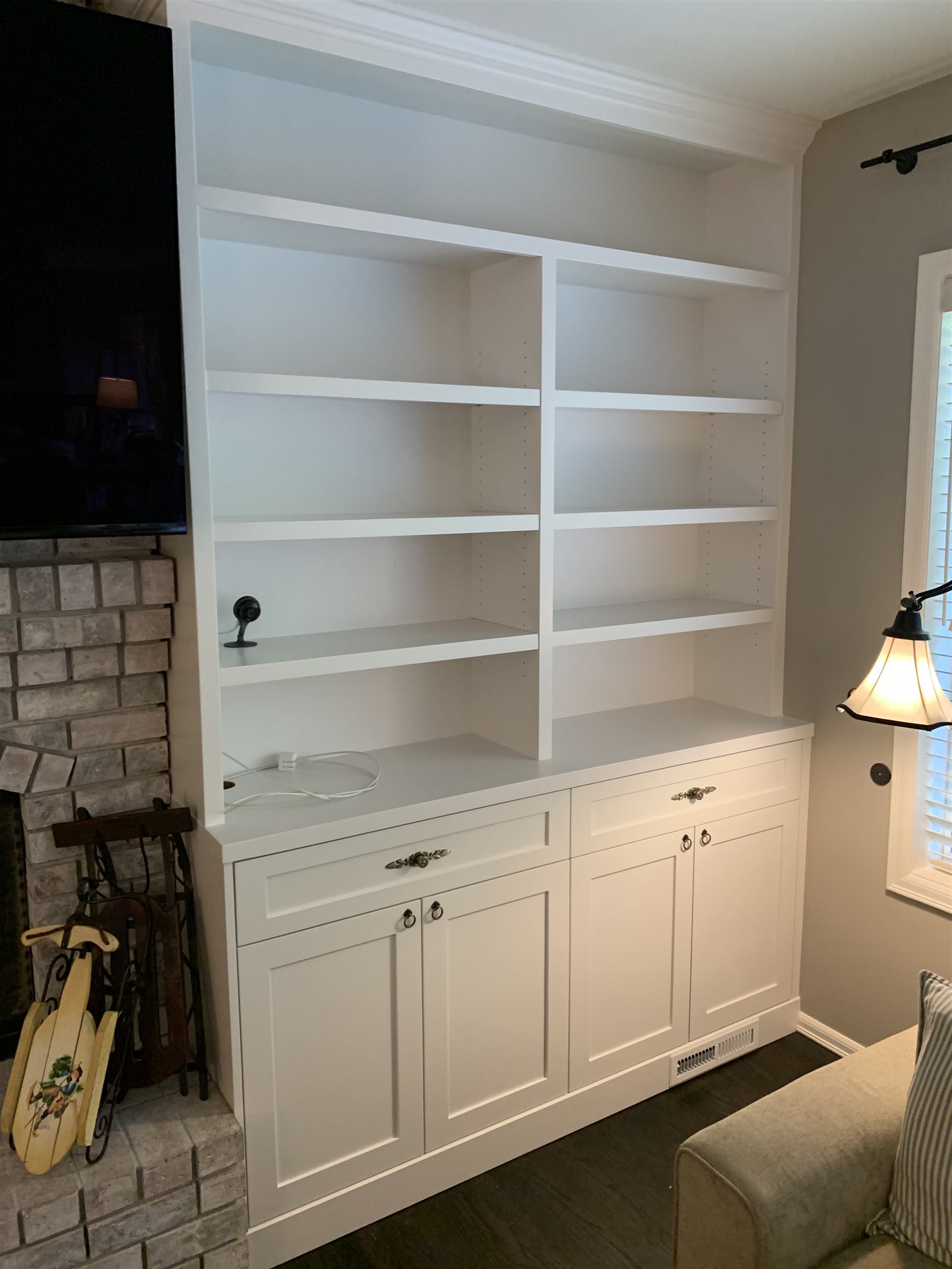 White built-in shelving and cabinetry beside a brick fireplace