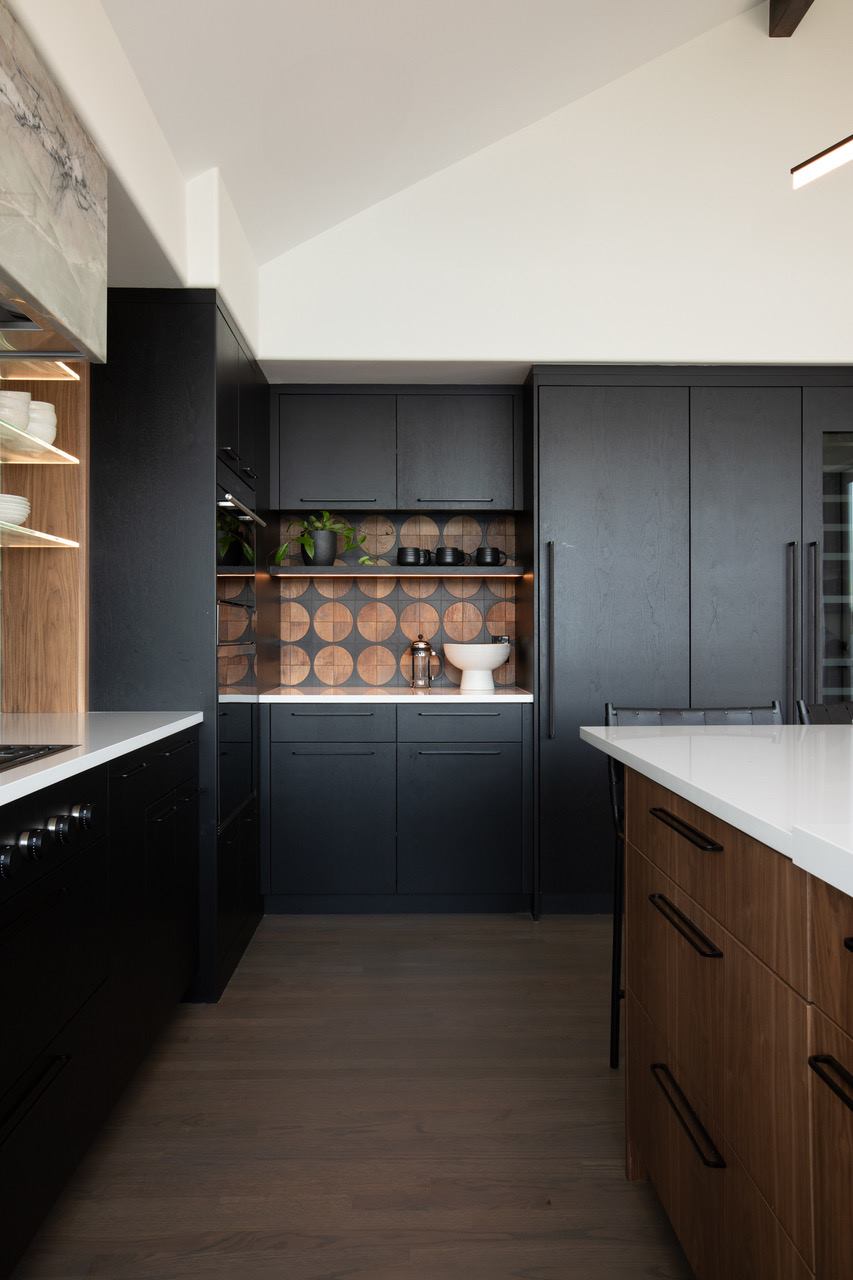Modern matte black kitchen cabinetry with warm walnut wood accents and a circular tile backsplash