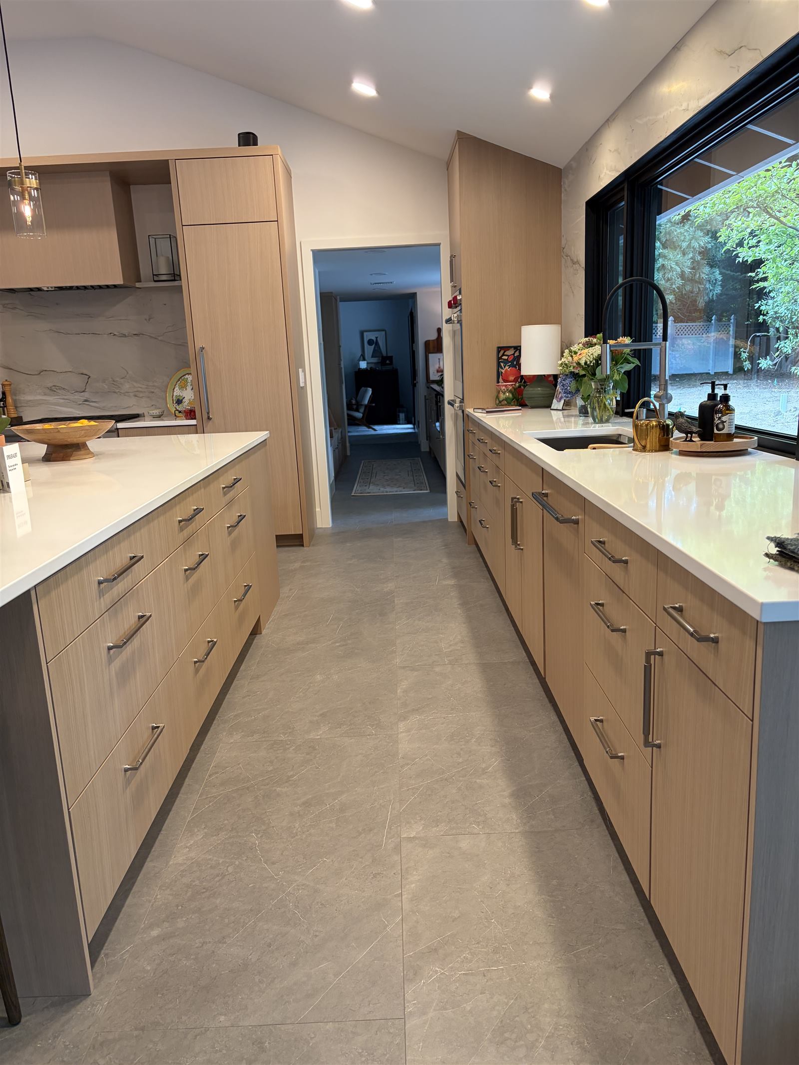Bright kitchen with light oak cabinetry and a full-height stone slab backsplash