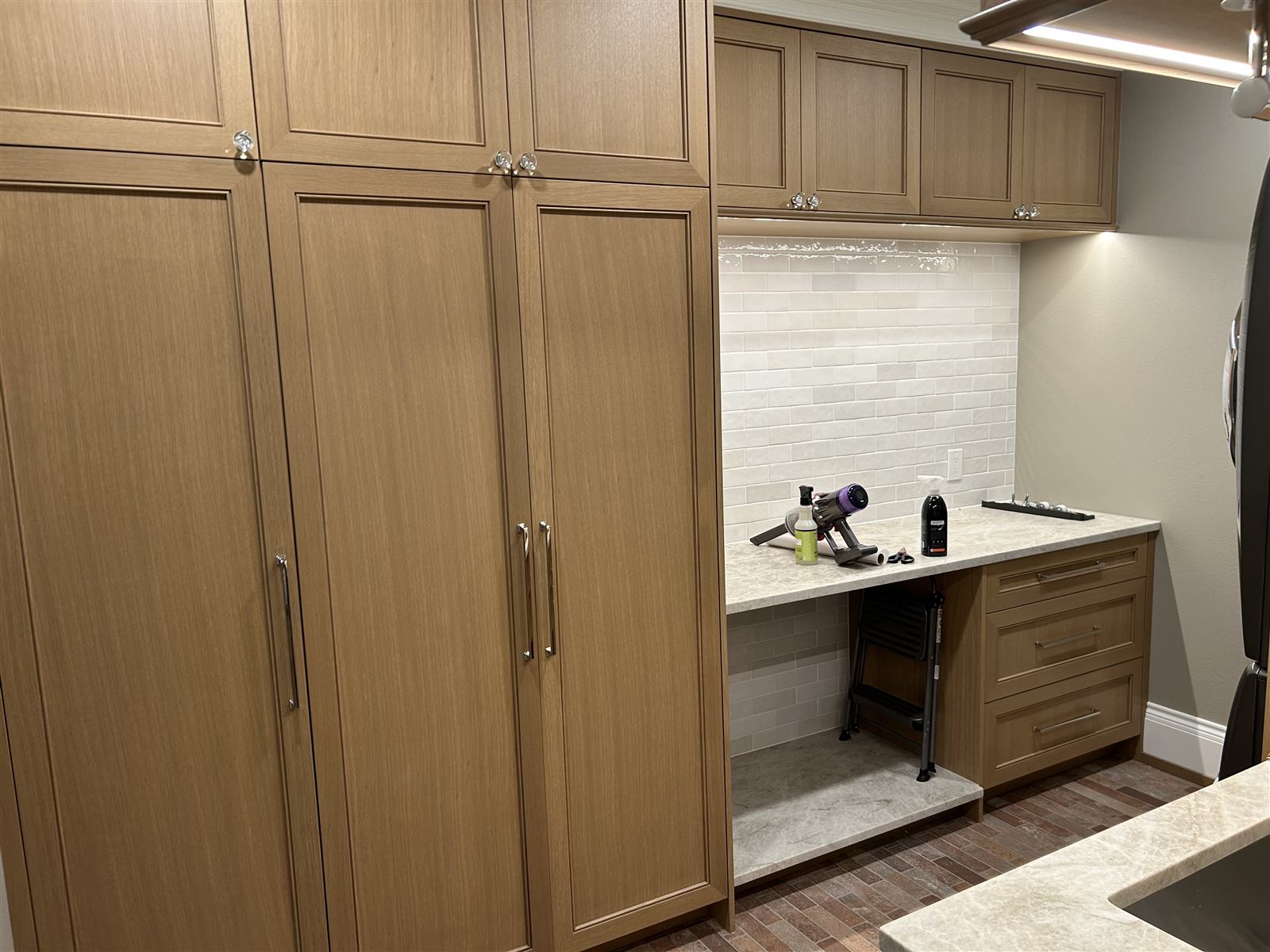 Tall oak pantry cabinets and a built-in fold-down counter in a laundry and utility room