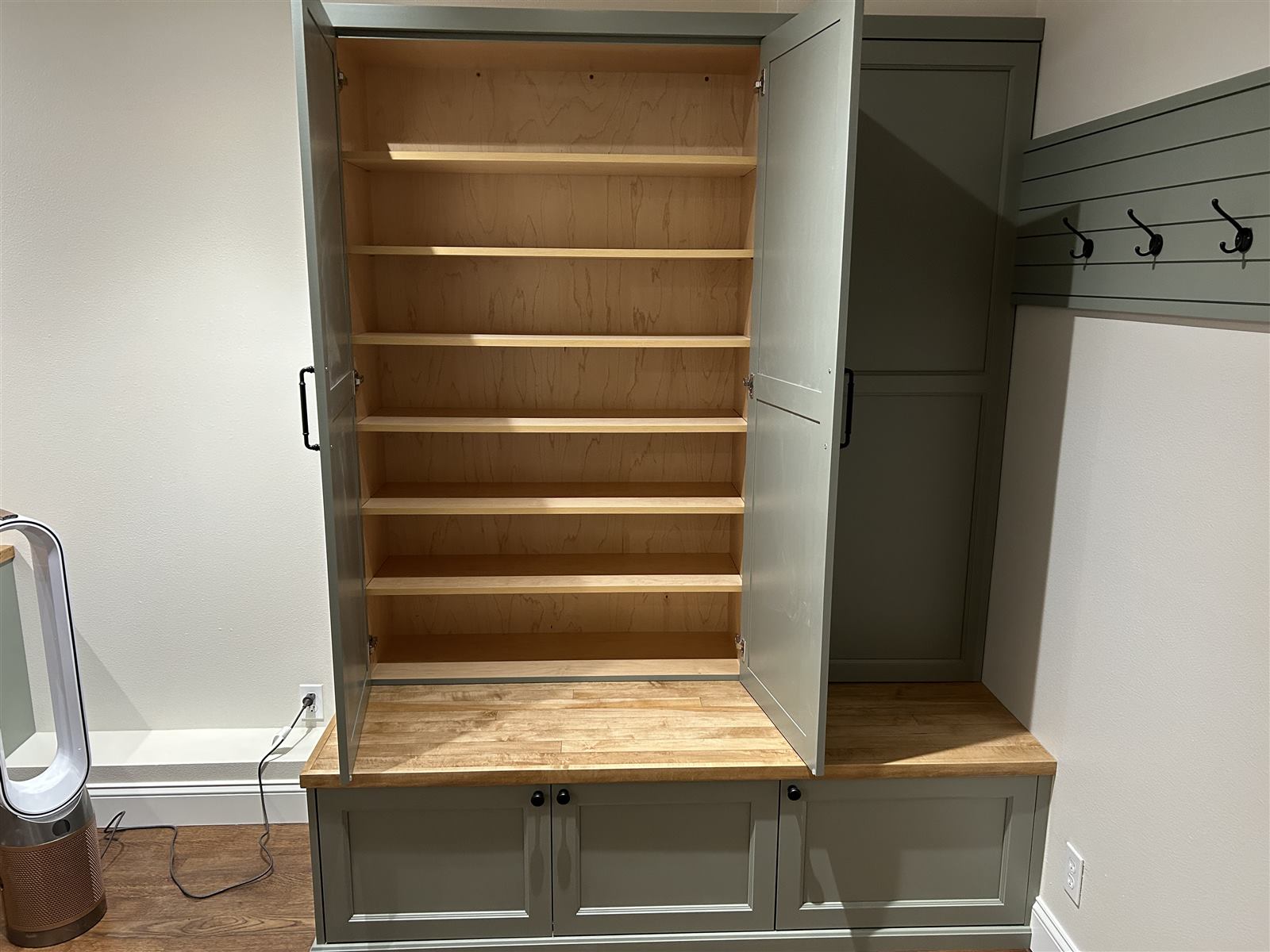 Sage green mudroom cabinet with open shelving, a butcher block bench top, and coat hooks